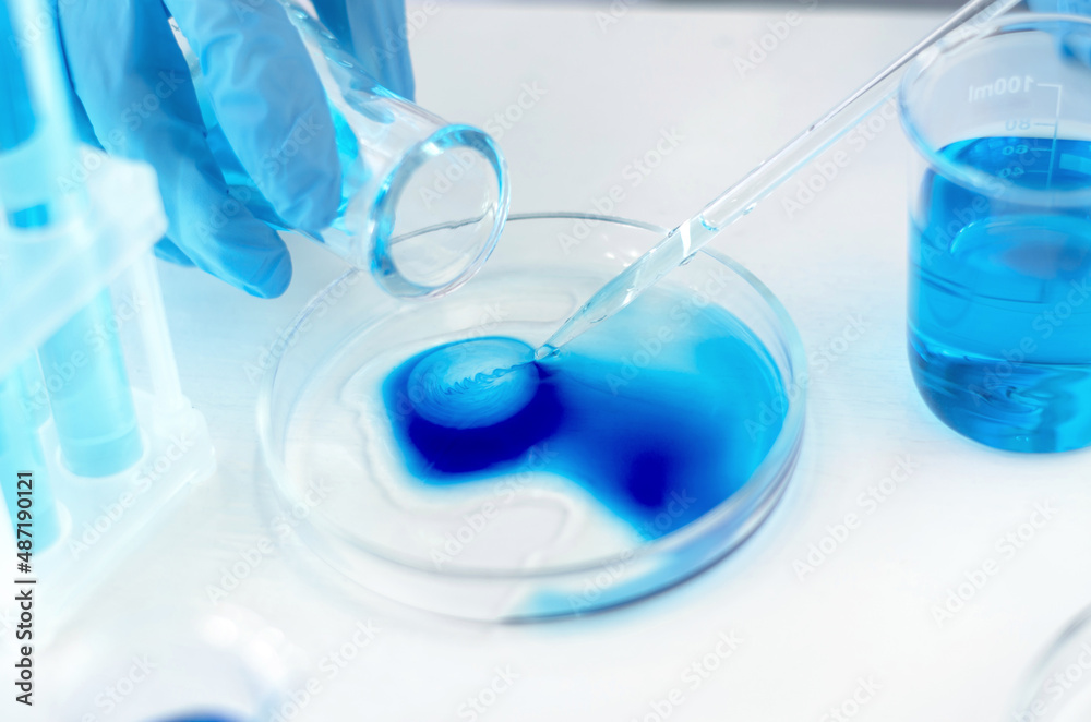 Hands of a scientist with a laboratory pipette. Equipment for chemical experiments. Scientist doing laboratory research Hands of a scientist with a laboratory pipette. Equipment for chemical experiments. Scientist doing laboratory research