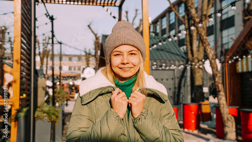 Beautiful blonde woman looks with a smile while standing outdoors. Perfect weather for hanging out with friends. Urban art space with street food