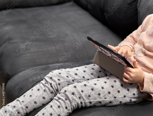 unrecognizable girl sitting on the sofa using a tablet