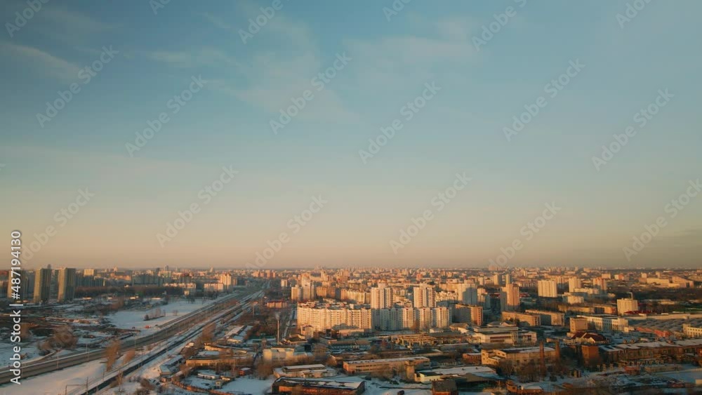 Suburb of a big city. City block from the height of the flight. City highway with busy traffic. Winter cityscape. Golden hour at sunset. Aerial photography.