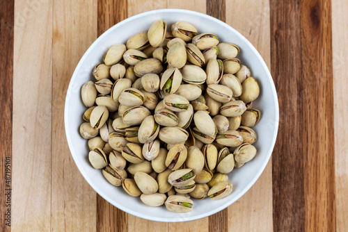 Bowl of pistachios on a butcher board background.  Centered.