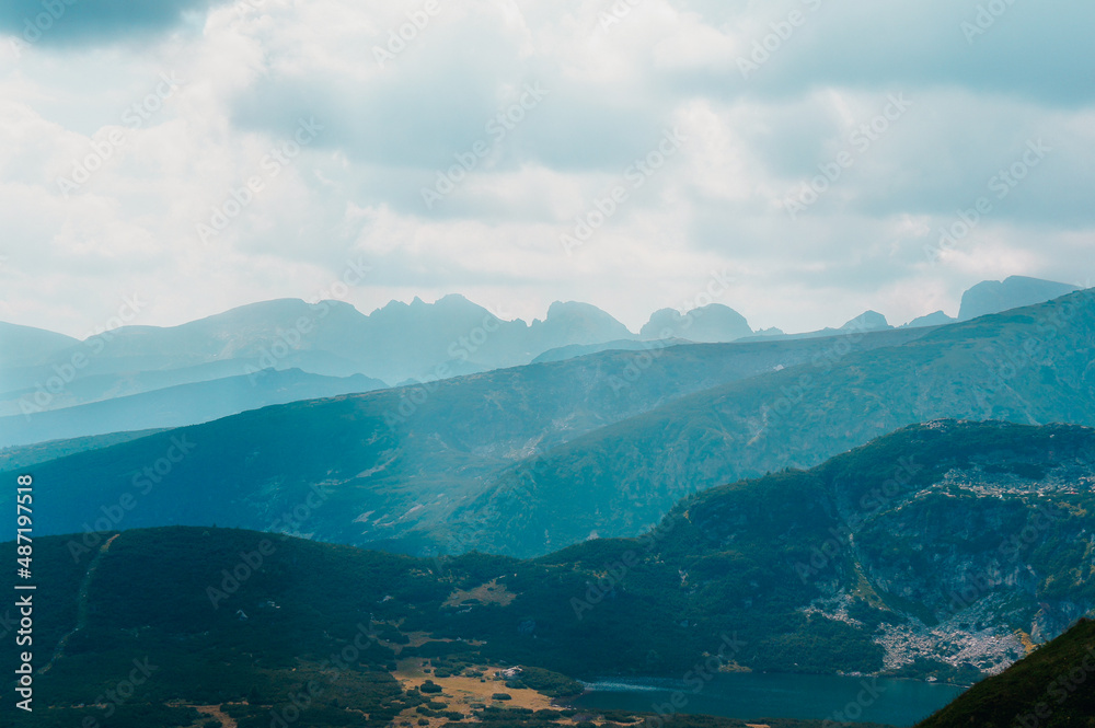 Obraz premium Mountain range with nestled lake clouds and mist covering forests
