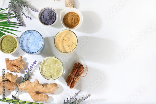 Assortment of colorful Japanese tea latte, green, blue, pink moon milk, golden milk, ginger and cinnamon, top view. Fashionable healthy drink has anti-inflammatory properties, selective focus photo