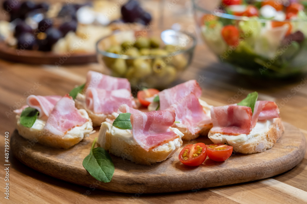 Close-up of sandwiches with bacon and tomatoes on wooden board on dining table