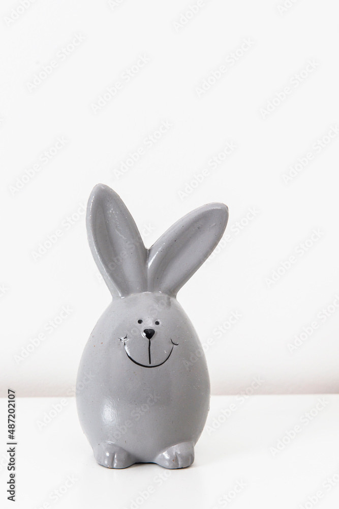 Mock up white frame with modern ceramic easter grey bunny decor on a shelf. White color scheme. Mock up white frame with modern ceramic easter grey bunny decor on a shelf. White color scheme.