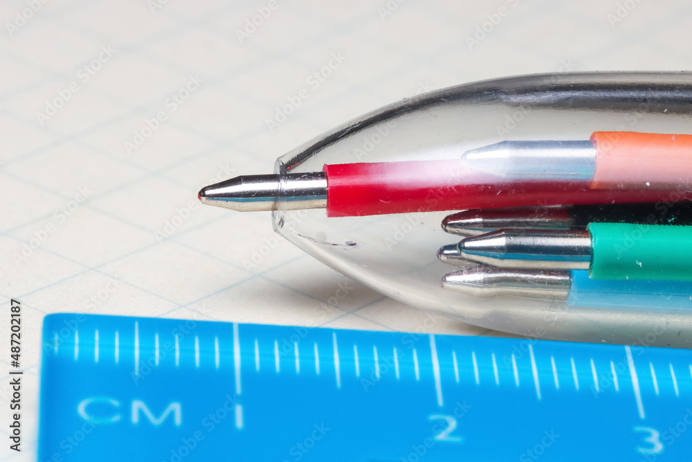 Multi color ball point pen and ruler on a graphing paper Multi color ball point pen and ruler on a graphing paper