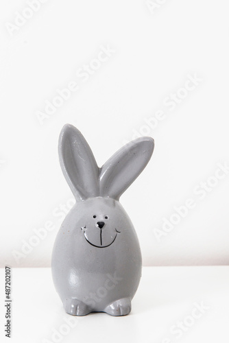 Mock up white frame with modern ceramic easter grey bunny decor on a shelf. White color scheme.