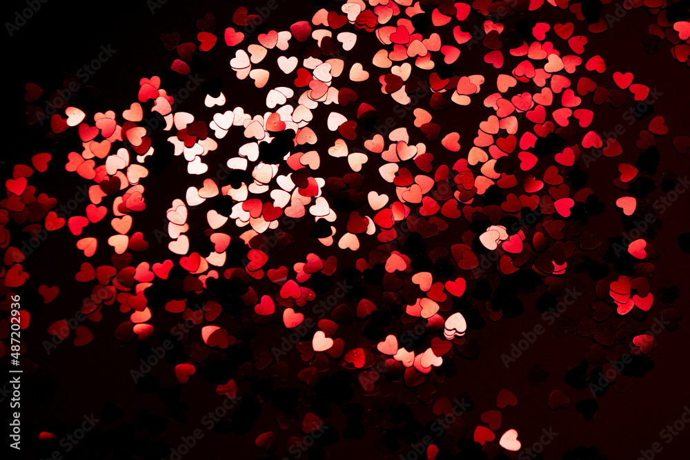 red festive confetti in the shape of a heart on a black background