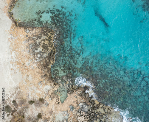 Drone aerial of rocky sea coast with transparent turquoise water. Seascape top view