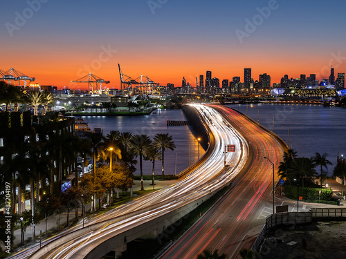 Fotografía Colorful sunset over Miami Downtown as seen from Miami Beach, long exposure of moving traffic over MacArthur Causeway, Florida, USA