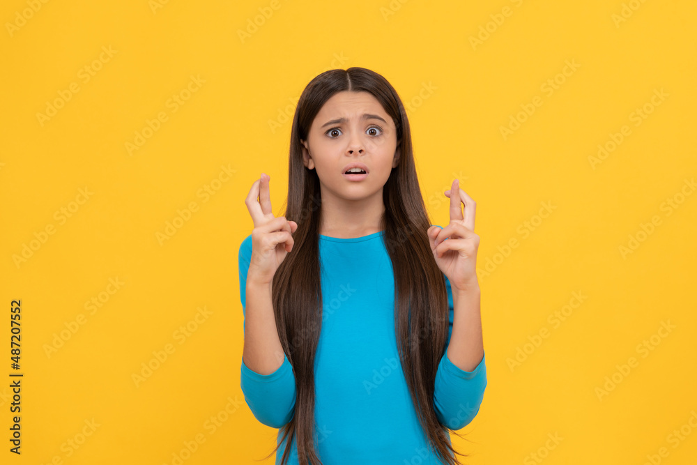 confused child making wish for luck with crossed fingers on yellow background, dream confused child making wish for luck with crossed fingers on yellow background, dream