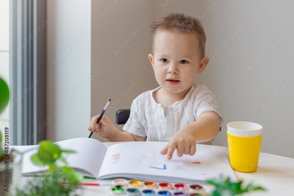 happy kid paints with a brush with watercolor paints, creativity and learning happy kid paints with a brush with watercolor paints, creativity and learning