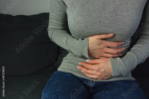 Woman suffering stomach ache sitting on a couch