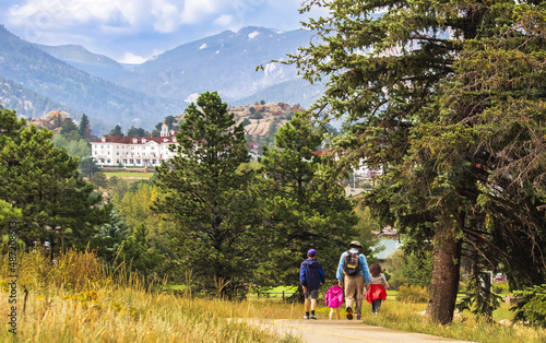 Three generations of family hiking near Estes Park, Colorado, in summer; building and mountains in background photo