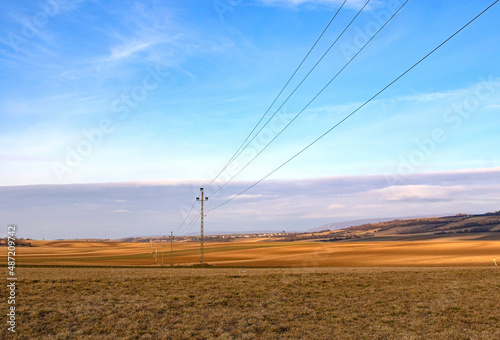 Rural field with a high-voltage pole line crossing the landscape
