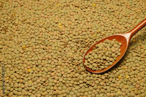Green lentils scattered close-up with a spoon.