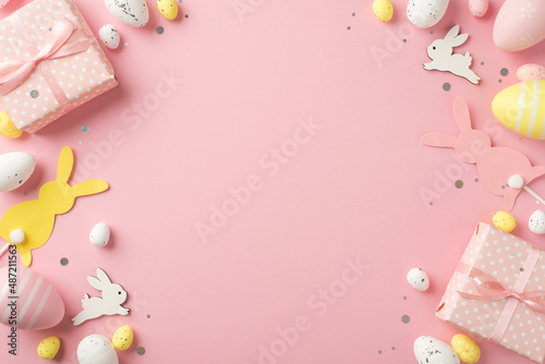 Top view photo of easter decorations gift boxes confetti easter bunnies pink yellow and white easter eggs on isolated pastel pink background with copyspace © ActionGP