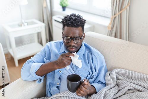 Canvas Print Ill african young man covered with blanket blowing running nose got fever caught