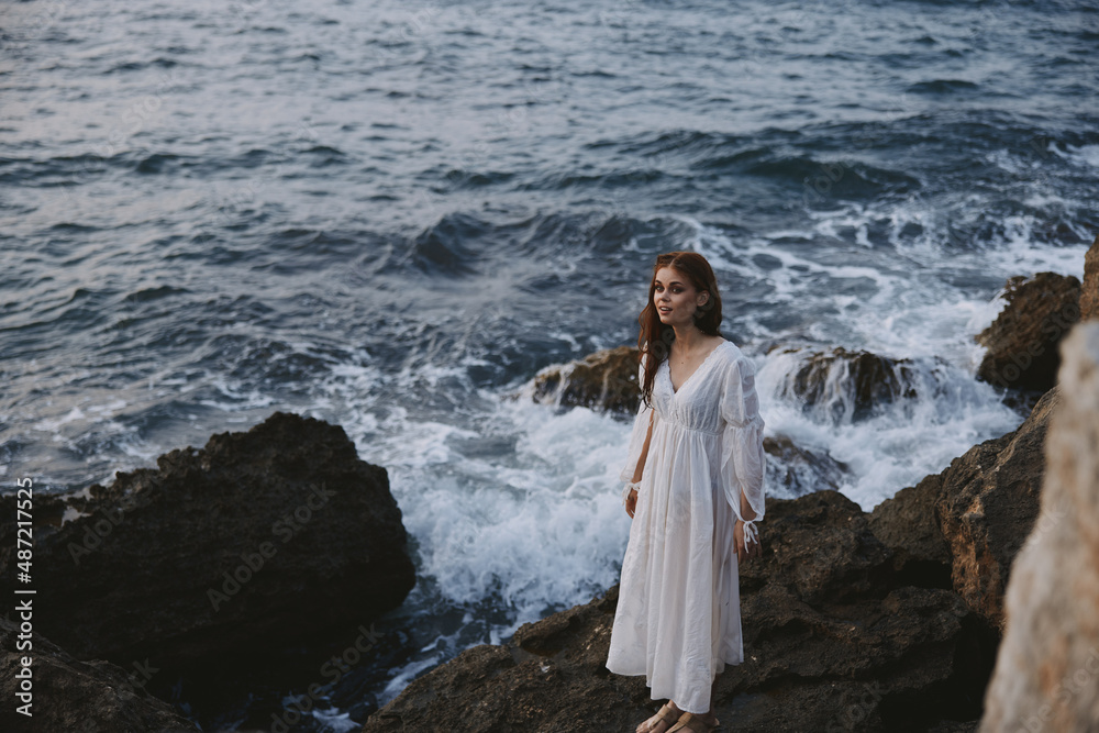 a woman in a wedding dress stands by the ocean on a cliff unaltered