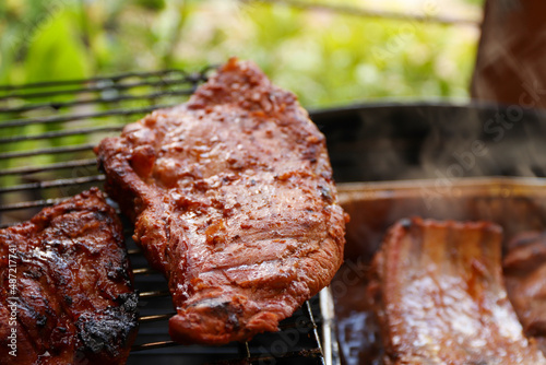 Marinated pork on the hot grill during a summer day. Barbecue party - crispy meat on the grill on the terrace.