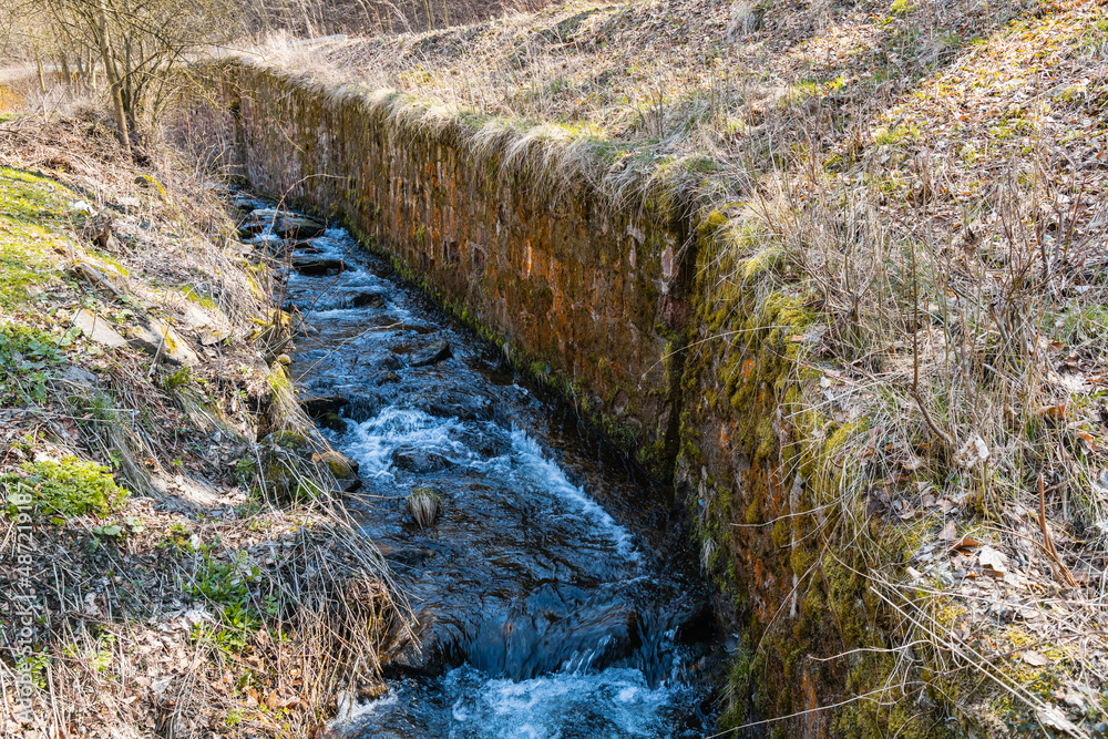Long mountain stream next to mountain trail with high wall next to stream Long mountain stream next to mountain trail with high wall next to stream