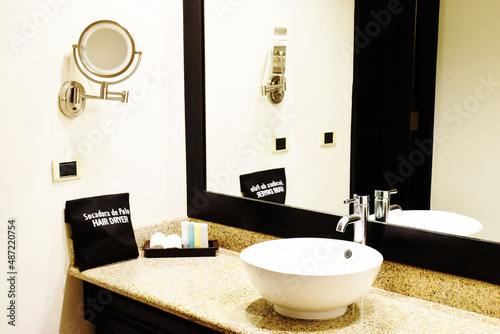 Tocador en una habitación de hotel. Artículos de cuidado personal, lavamanos, espejo, secador de pelo y toallas. photo