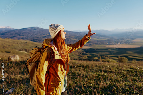 woman tourist in a yellow jacket in a hat backpack travel mountains sunny day