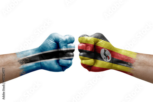 Two hands punch to each others on white background. Country flags painted fists, conflict crisis concept between botswana and uganda