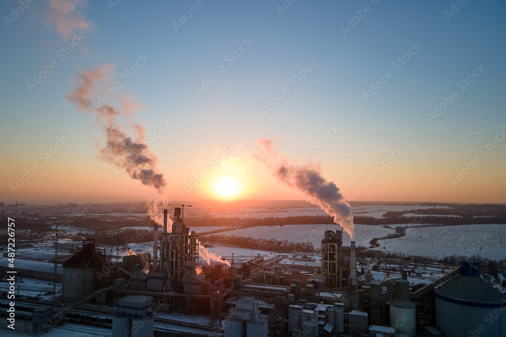 Aerial view of cement factory tower with high concrete plant structure at industrial production area at sunset. Manufacturing and global industry concept