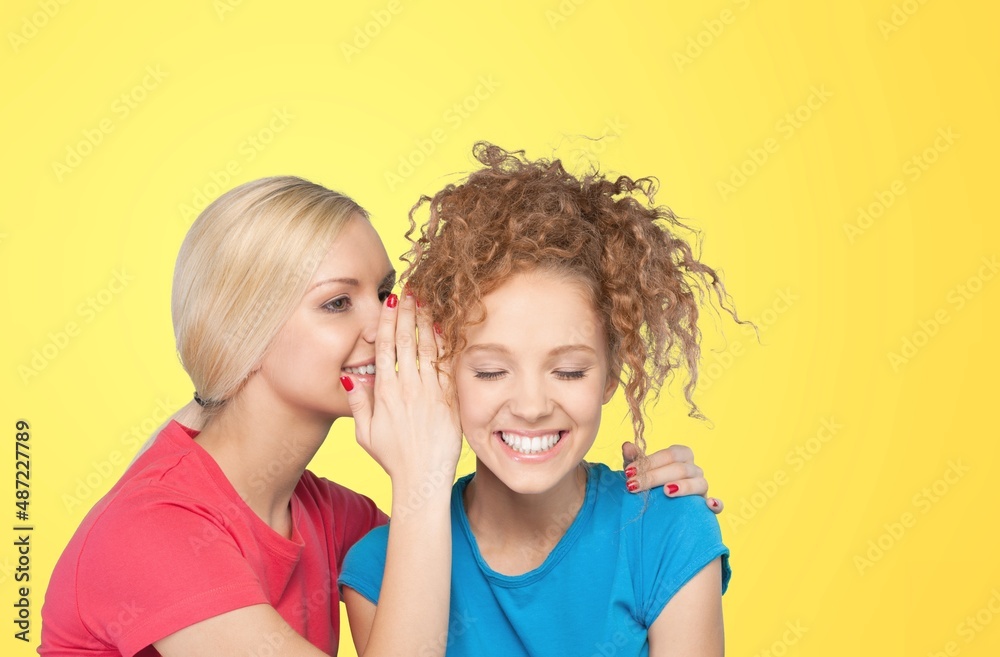 Young woman surprised when her friend talks whispering in her ear Young woman surprised when her friend talks whispering in her ear