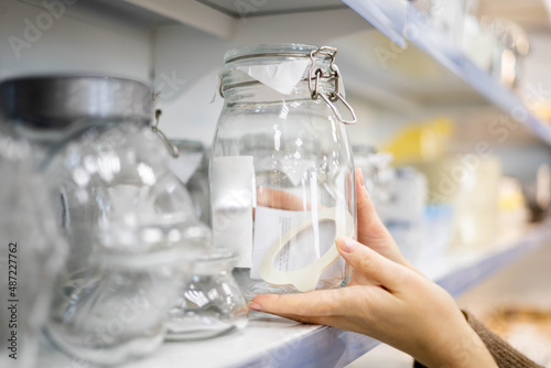 Woman choosing glass jar container for food storage kitchen space organizing enjoying shopping