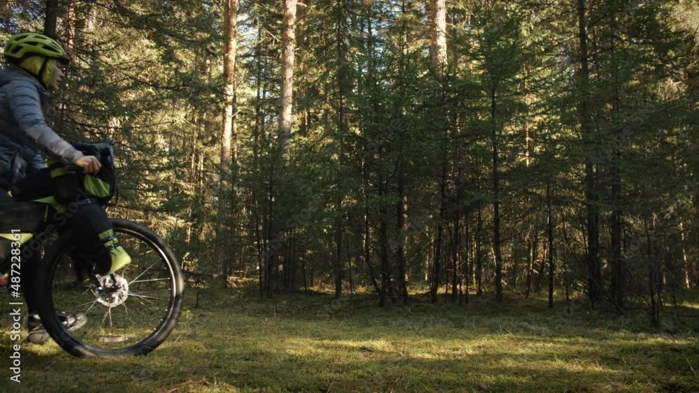 The woman travel on mixed terrain cycle touring with bike bikepacking outdoor. The traveler journey with bicycle bags. Stylish bikepacking, bike, sportswear in green black colors. Magic forest park. The woman travel on mixed terrain cycle touring with bike bikepacking outdoor. The traveler journey with bicycle bags. Stylish bikepacking, bike, sportswear in green black colors. Magic forest park.