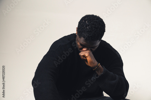 beaten man of color with fist in his face looking down white background - waist up shot. High-quality photo © PoppyPix