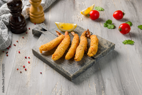 fried tempura shrimps with lemon on wooden board
