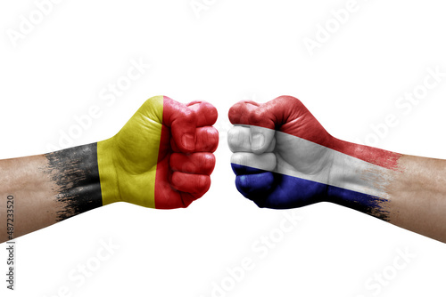 Two hands punch to each others on white background. Country flags painted fists, conflict crisis concept between belgium and netherlands