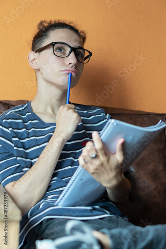 pensive teenager with glasses and a notebook in his hands 