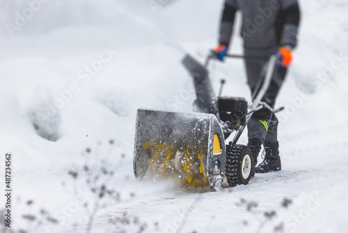 Billede på lærred Process of removing snow with portable blower machine, worker dressed in overall