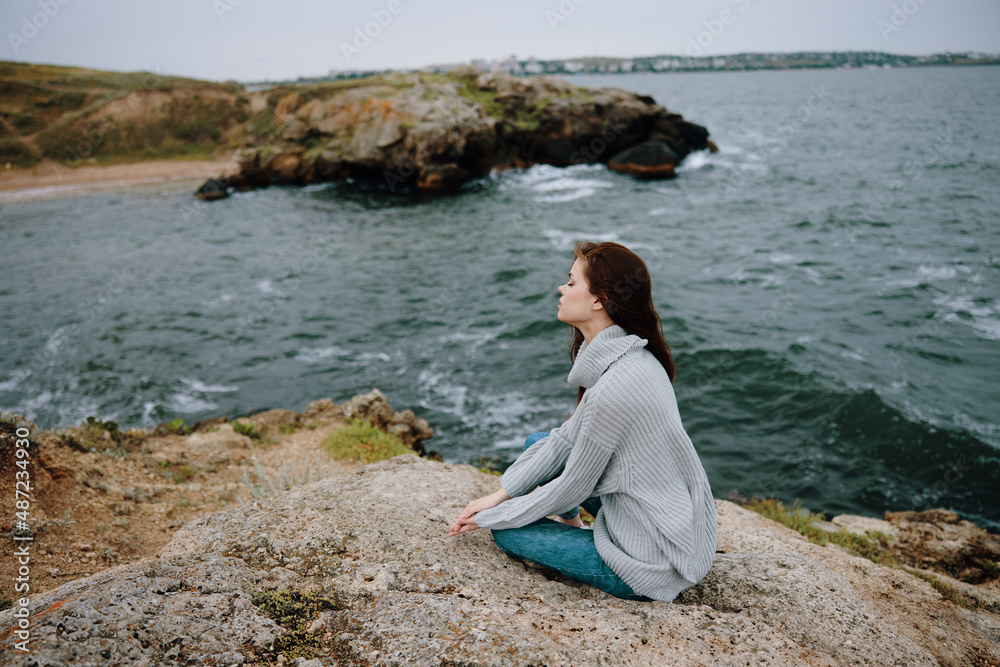 woman seated on the coast sweater landscape female relaxing