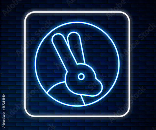 Glowing neon line Animal cruelty free with rabbit icon isolated on brick wall background. Vector