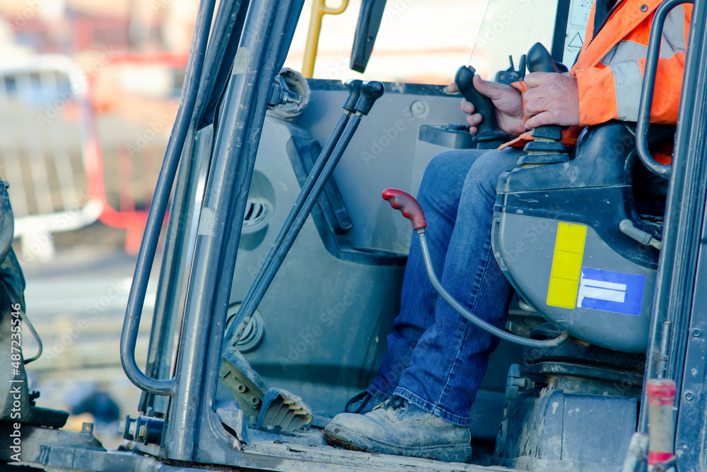 Fototapeta premium Excavator driver at work in construction site 