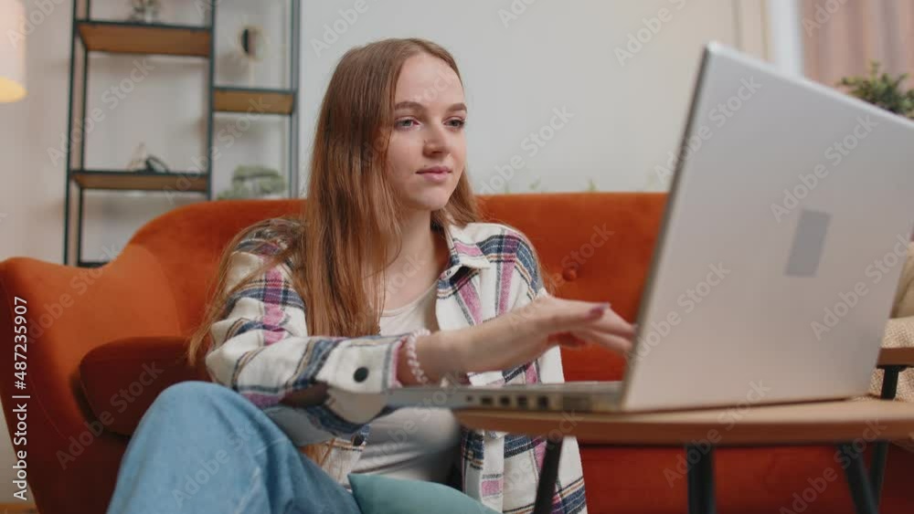 Young woman using laptop computer sitting on floor working from home office. Adult girl elearning, browsing internet, doing online shopping, remote job ordering food delivery on pc tech in living room