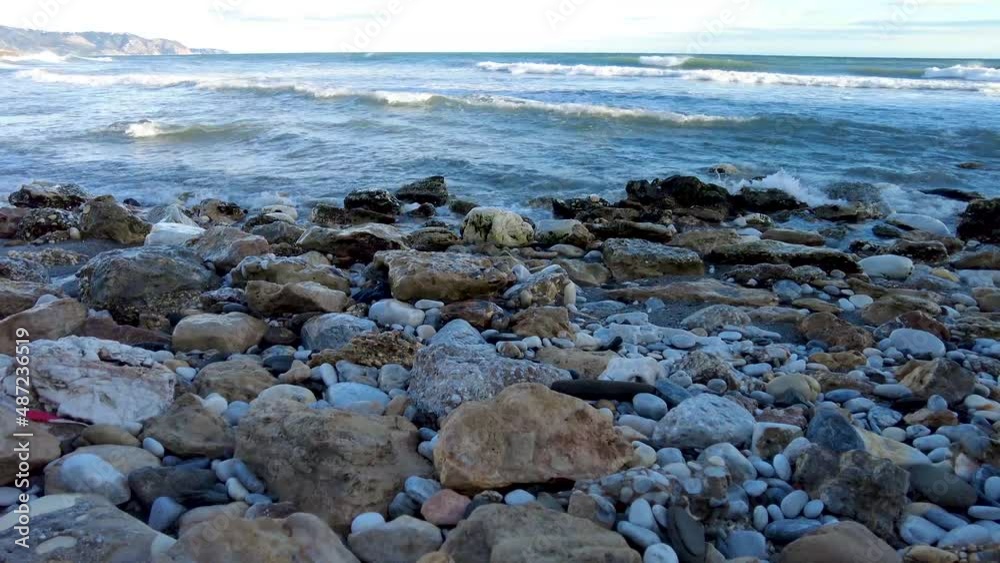 Plenty of stones on a beach outside Nerja in Spain. Waves rolling in on a stony beach. natural stone beach on the southern coast of Spain. Waves crashing in on some stones at the beach. Plenty of stones on a beach outside Nerja in Spain. Waves rolling in on a stony beach. natural stone beach on the southern coast of Spain. Waves crashing in on some stones at the beach.