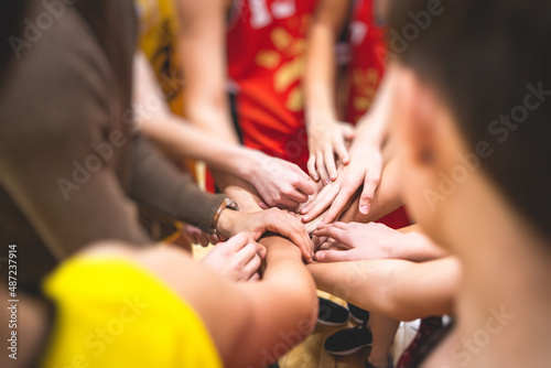 Team of kids children basketball players stacking hands in the court, sports team together holding hands getting ready for the game, playing indoor basketball, team talk with coach, close up of hands