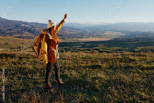 woman in a yellow jacket in a hat backpack travel mountains Lifestyle