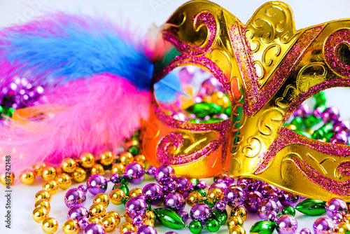 Golden carnival mask and colorful beads on white background. Closeup symbol of Mardi Gras or Fat Tuesday.