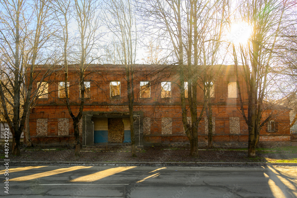 old abandoned red brick building in the rays of the bright afternoon sun on a clear spring day 
