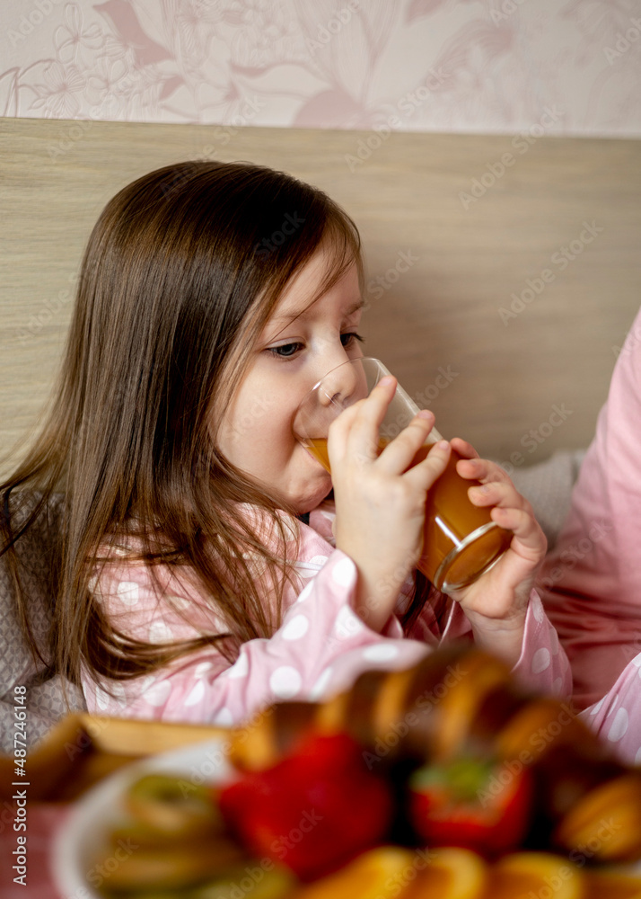 Beautiful young woman with a little cute girl spend time together at home, sitting on the bed. Beautiful young woman with a little cute girl spend time together at home, sitting on the bed.