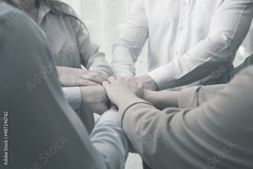 Group of people holding their hands together, closeup. Black and white effect