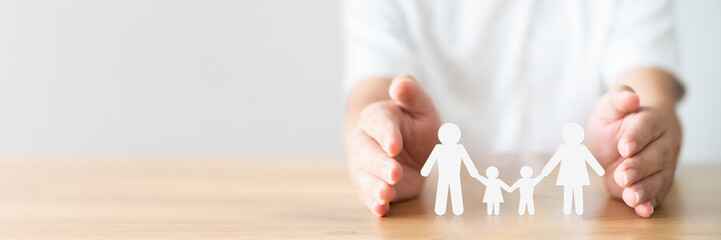Hand protecting family on wood table. Healthcare and life insurance concept