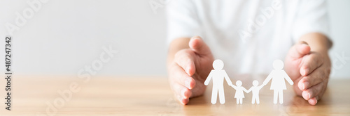 Hand protecting family on wood table. Healthcare and life insurance concept photo